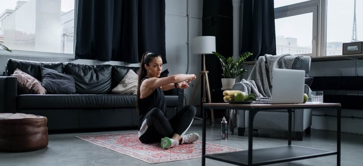 Woman doing exercise at home, sitting and stretching in a cozy living room.