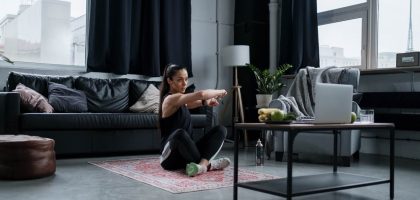 Woman doing exercise at home, sitting and stretching in a cozy living room.