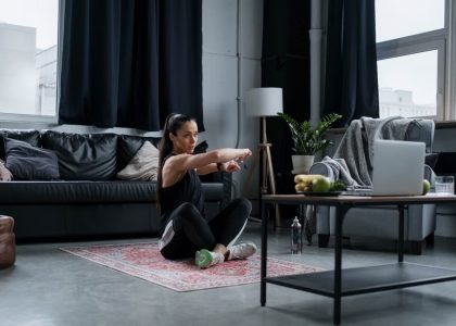 Woman doing exercise at home, sitting and stretching in a cozy living room.